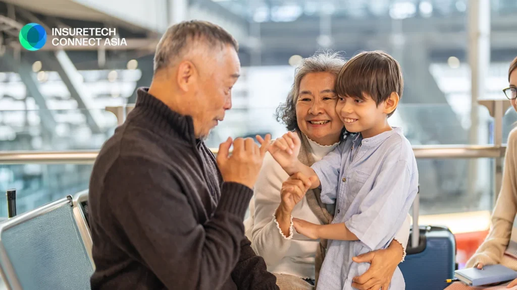Grandfather, grandmother, and grandson share a joyful moment together in an airport lounge, with InsureTech Connect Asia logo in the corner.