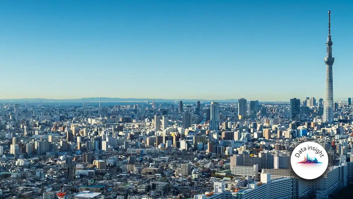 Wide Tokyo city skyline with Tokyo Skytree on the right and a circular Data insight logo in the lower-right corner, clear blue sky above.