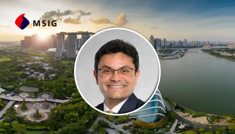 Portrait of a smiling man in a dark suit and glasses centered over a Singapore skyline with the MSIG logo in the top left corner, creating a corporate banner feel.