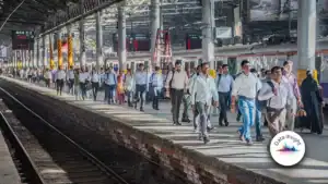 Crowded railway platform with hundreds of commuters walking beside a stationary train under a shelter on a busy station.
