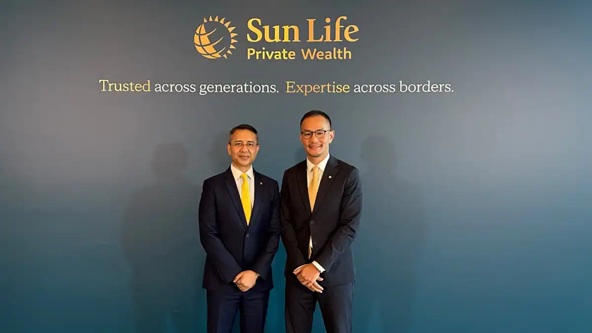 Two men in dark suits with yellow ties stand in front of a Sun Life Private Wealth backdrop with slogan, posing for a photo at a formal event.