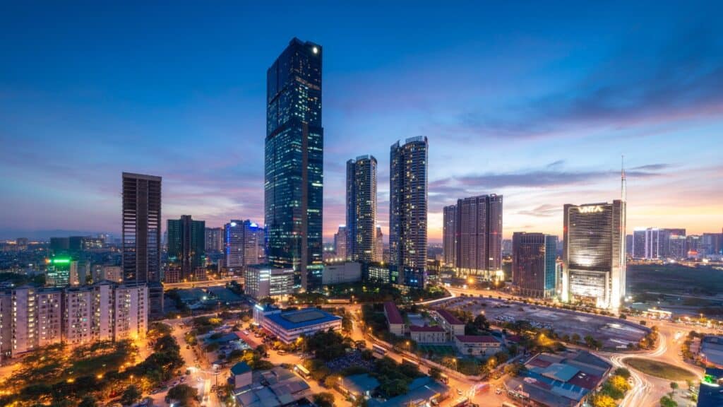 Dusk city skyline with tall glass skyscrapers and illuminated streets below.