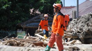 Rescue workers in orange gear amid debris after US storm, Swiss Re catastrophe report.