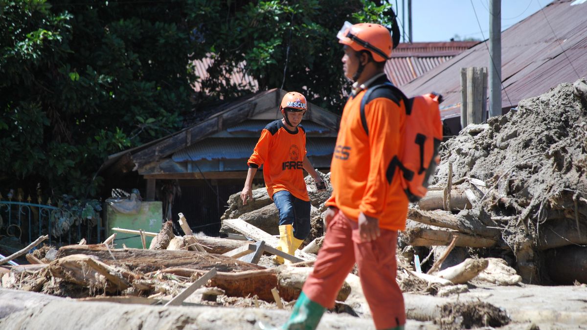 Rescue workers in orange gear amid debris after US storm, Swiss Re catastrophe report.