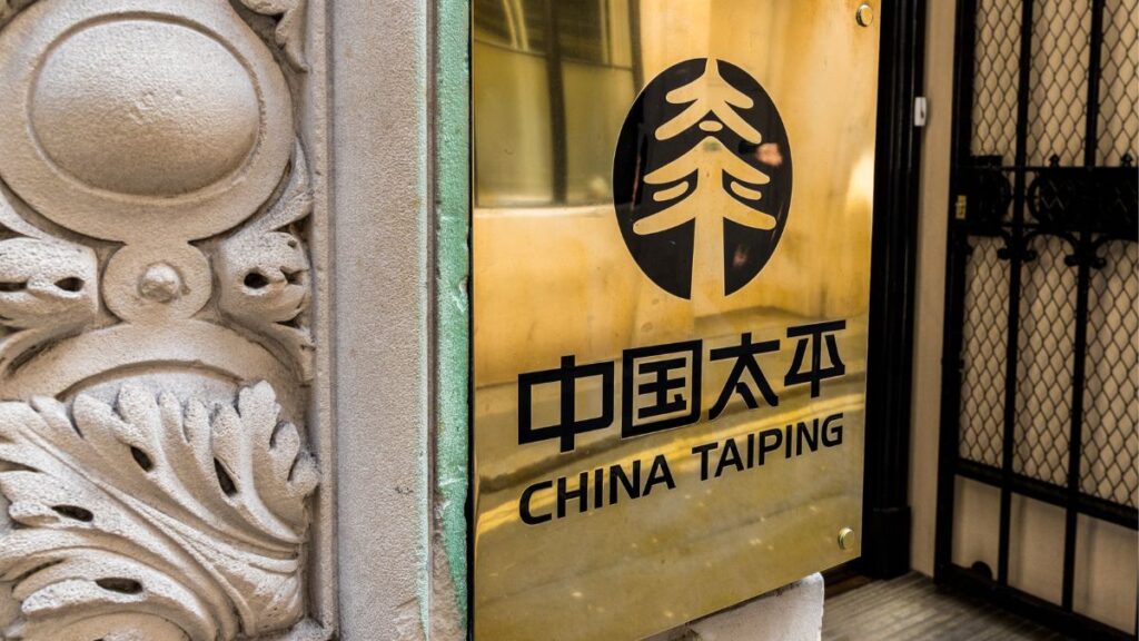 Gold metal plaque with the China Taiping logo and the text 中国太平 / CHINA TAIPING on a stone wall near ornate carvings.
