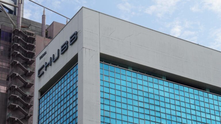 Chubb office building with large blue-tinted glass windows and a white concrete façade under a partly cloudy sky