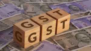 GST demand concept with Indian currency notes and wooden blocks spelling GST.