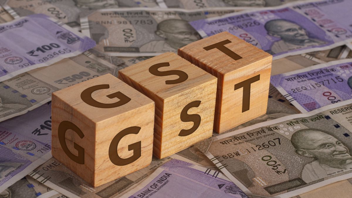 GST demand concept with Indian currency notes and wooden blocks spelling GST.