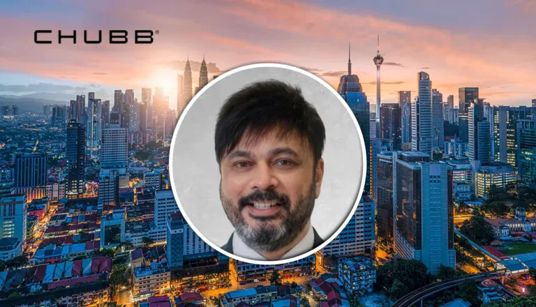 Chubb logo over a city skyline at sunset, with a circular portrait of a smiling man centered in the image.