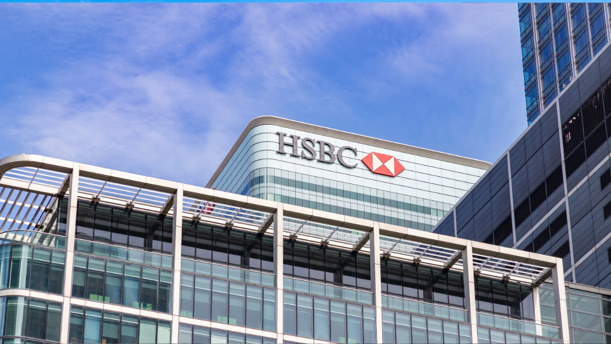 Modern glass office building with the HSBC logo against a clear blue sky.