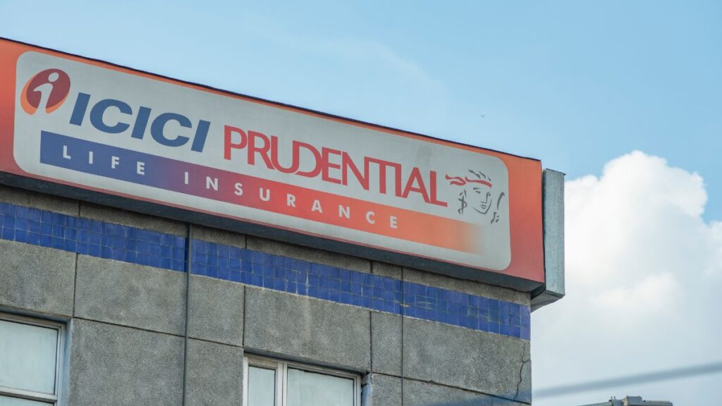 Sign on a building reads 'ICICI PRUDENTIAL LIFE INSURANCE' with a small logo against a blue sky.”,