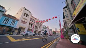 Singapore life new business premiums rise 28.1% in Q2 A cyclist rides down a urban street lined with colorful storefronts and hanging lanterns across the road at dusk/light traffic.
