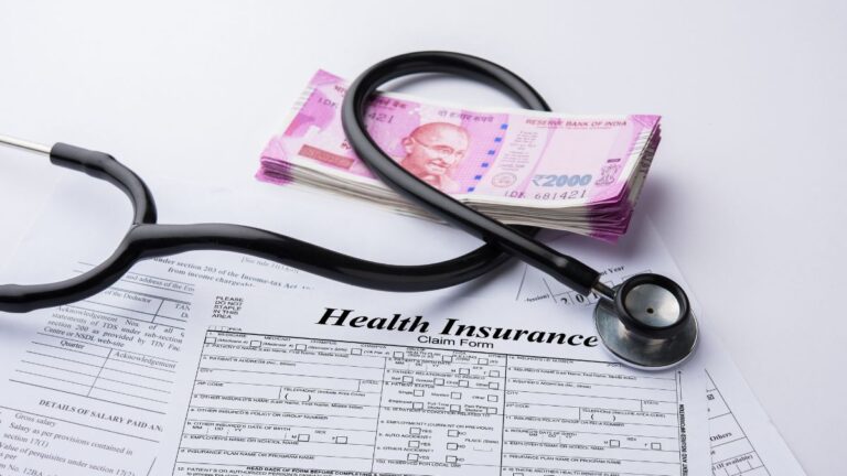 Health insurance claim form with a stethoscope and a stack of Indian ₹2000 notes beside it.