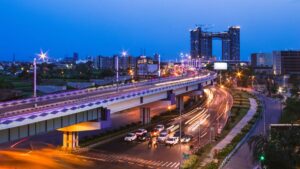 Urban highway in India with city skyline and ongoing construction at dusk.