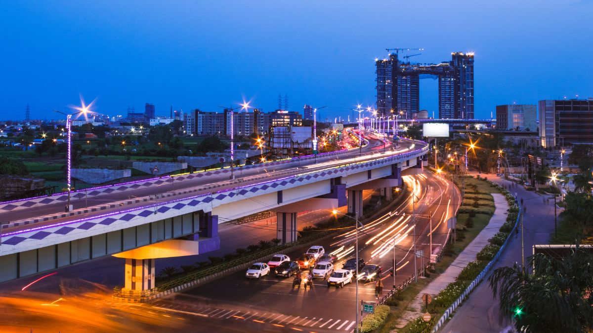 Urban highway in India with city skyline and ongoing construction at dusk.
