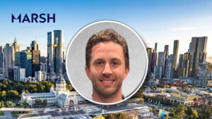 Marsh Re Pacific hires Sean Langham as VP, facultative reinsurance City skyline with high-rise buildings and a large circular portrait of a smiling man overlaid in the center, with the MARSH logo visible on the left.