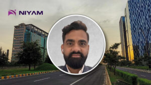 Corporate banner with NIYAM logo and a circular portrait of a man with a beard over a city street background.