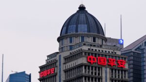 Tall office building with a glass dome and large red neon Chinese characters 中国平安 on the facade.