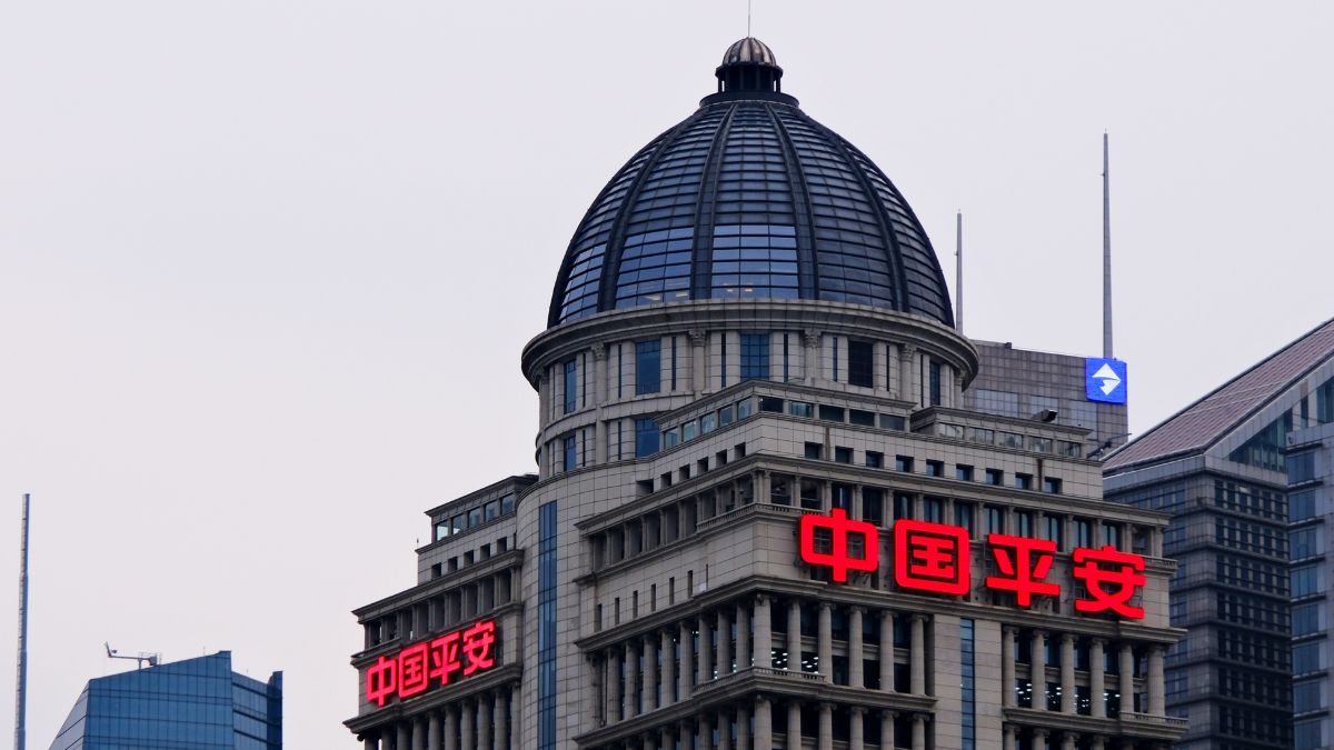 Tall office building with a glass dome and large red neon Chinese characters 中国平安 on the facade.