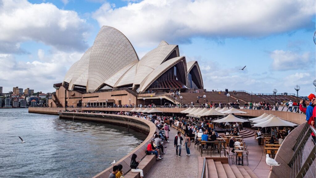 Sydney Opera House and Harbour Bridge in Australia with tourists and seagulls.