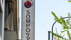 Vertical SOMPO sign with red circular logo mounted on a building.
