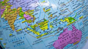 Close-up of a globe showing Southeast Asia and parts of India and Australia with country names highlighted in bright colors.