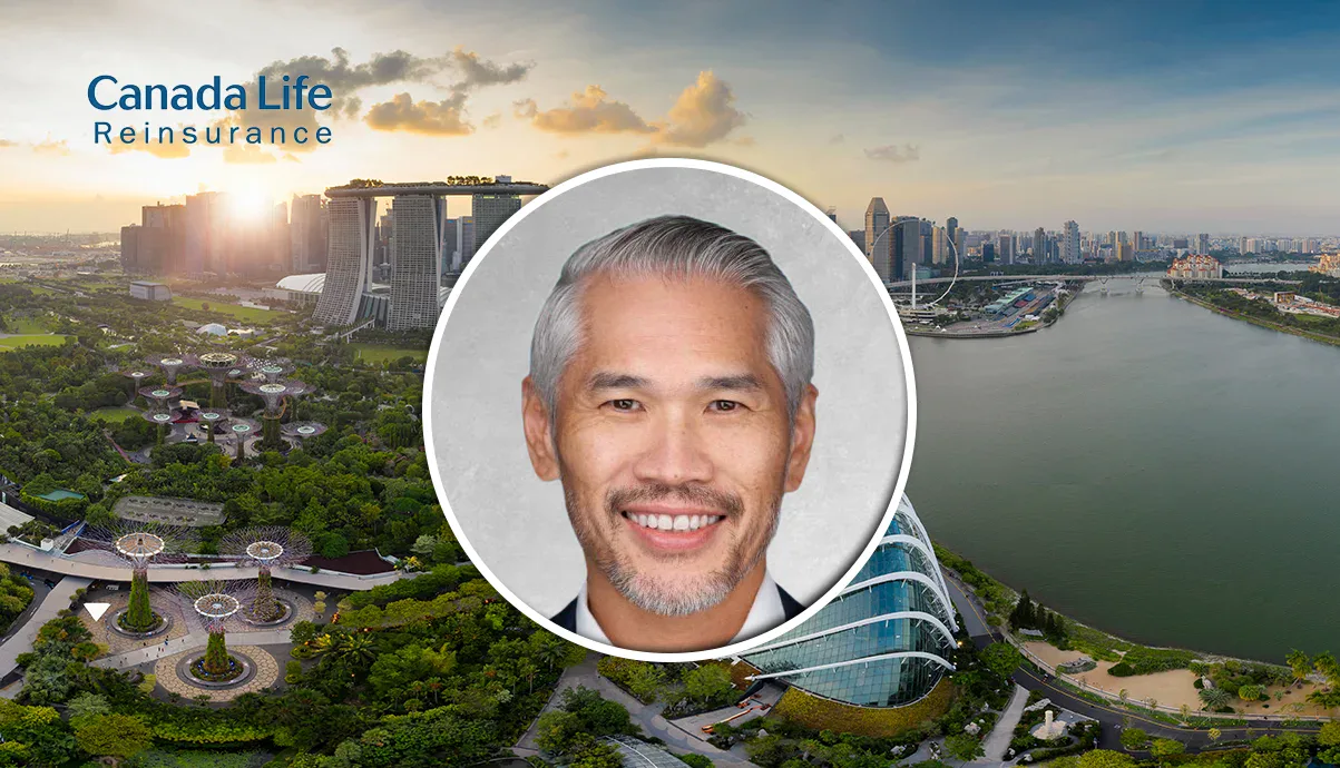Portrait of an Asian man with grey hair in front of Singapore skyline and river.