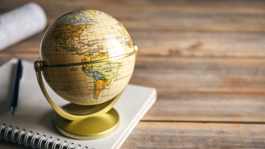 Small globe on a desk with a notebook and pen, representing global reinsurance sector.