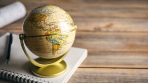 Small globe on a desk with a notebook and pen, representing global reinsurance sector.