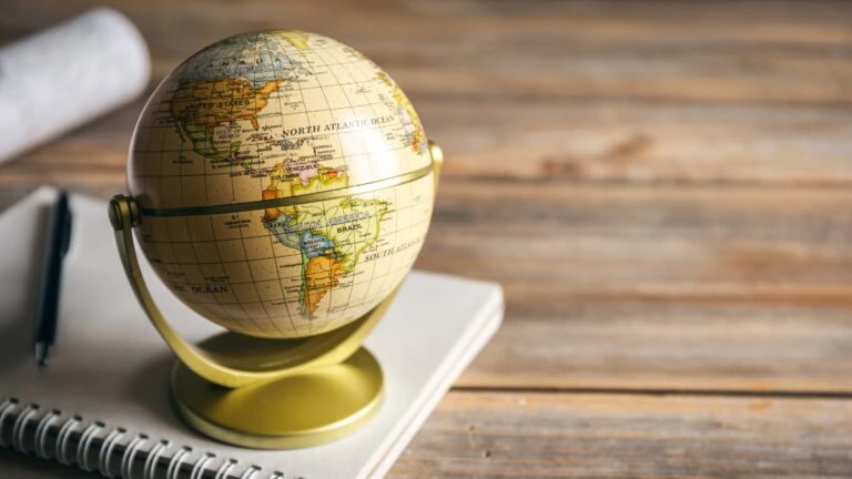 Small globe on a desk with a notebook and pen, representing global reinsurance sector.