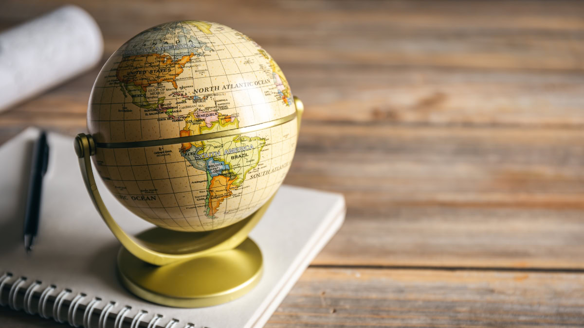 Small globe on a desk with a notebook and pen, representing global reinsurance sector.