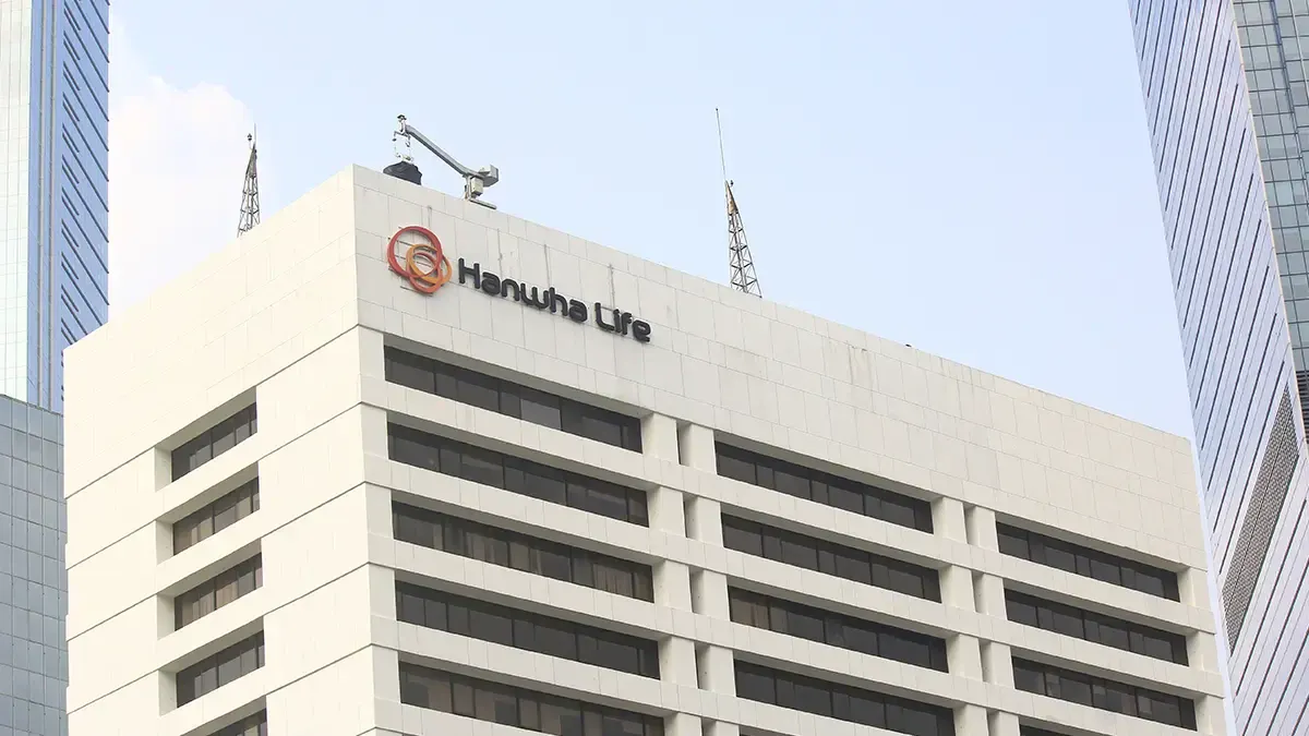 White corporate building with the Hanwha Life logo on the top corner, pale facade and dark windows.