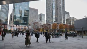 Japan life insurers' unrealised bond losses surge 60% as JGB yields rise — Report Busy urban plaza with pedestrians and modern glass skyscrapers in the background during autumn sunlightfall colors in trees behind them