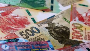 Several colorful banknotes in a pile, including a 500 yuan note and Hong Kong notes, scattered on a surface