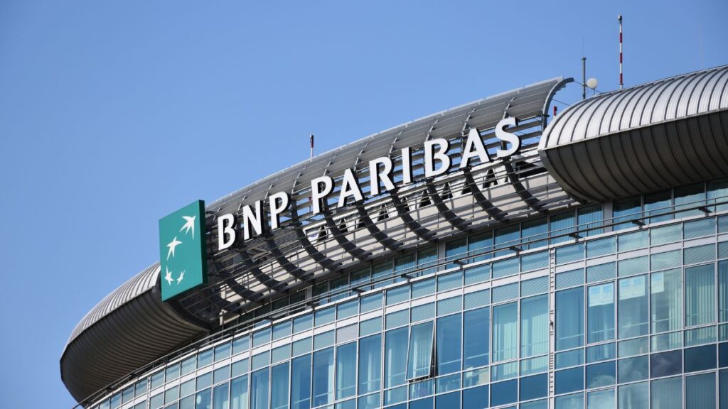 BNP Paribas sign atop a curved glass office building against a clear blue sky