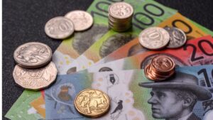 Australian banknotes and coins on a dark surface, showing colorful notes and metal coins scattered around.