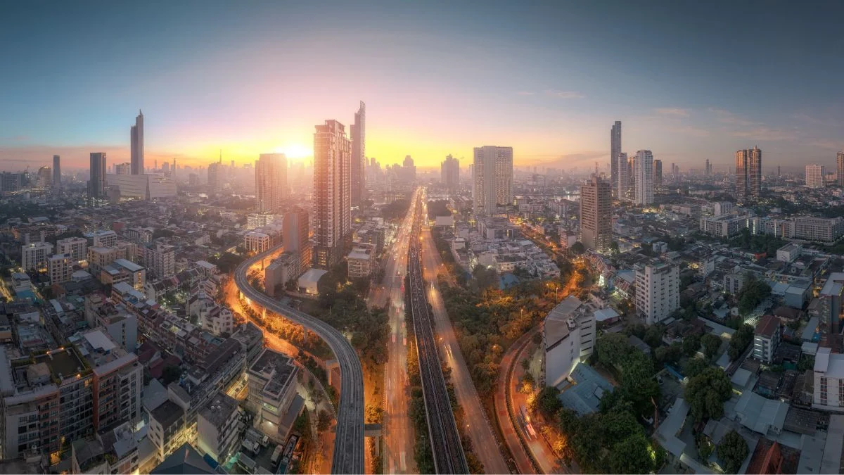 Panoramic city skyline at sunset with elevated rail lines curving through dense urban blocks