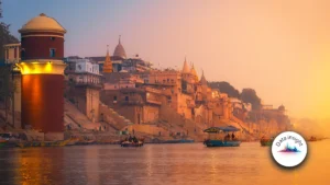 Sunset over the ghats of Varanasi along the Ganges, with boats on the water and a warm orange glow.