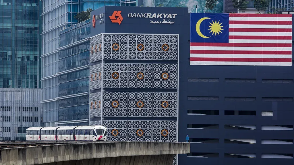 Bank Rakyat building in Malaysia with Malaysian flag, related to MNRB's Takaful sale.