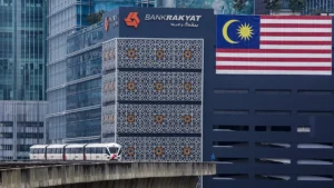 Bank Rakyat building in Malaysia with Malaysian flag, related to MNRB's Takaful sale.