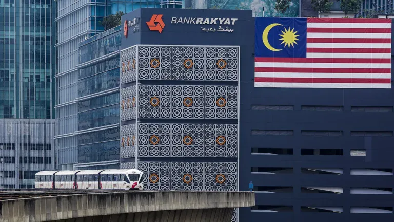 Bank Rakyat building in Malaysia with Malaysian flag, related to MNRB's Takaful sale.