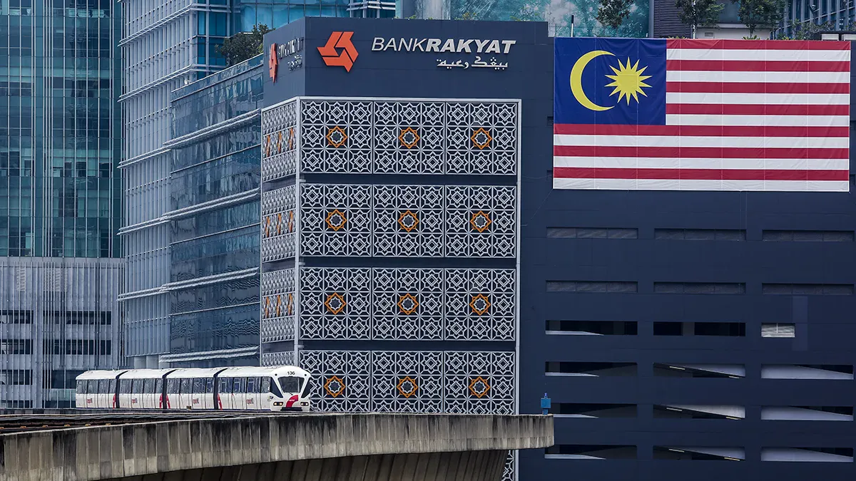 Bank Rakyat building in Malaysia with Malaysian flag, related to MNRB's Takaful sale.