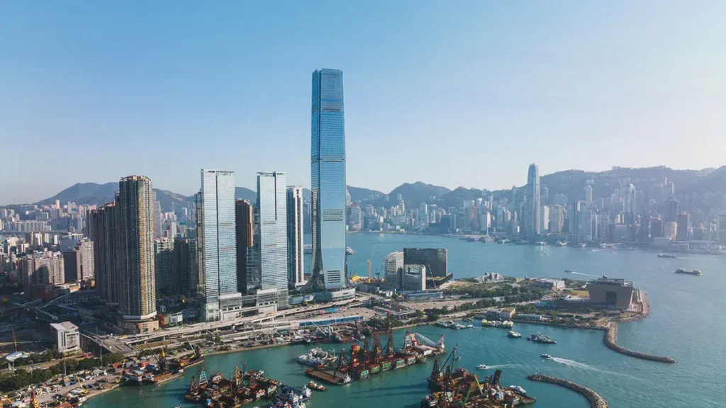 Wide city skyline of Hong Kong with tall skyscrapers along Victoria Harbour and hills in the distance