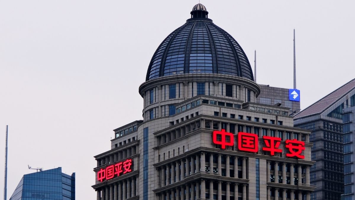 Tall office building with a glass-domed roof and red neon Chinese signage 中国平安 on the facade
