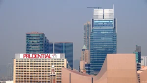 City skyline with tall glass skyscrapers and a beige building displaying a red Prudential sign in the foreground.