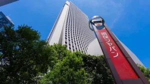 Tall skyscraper in Japan with a red sign and blue sky.