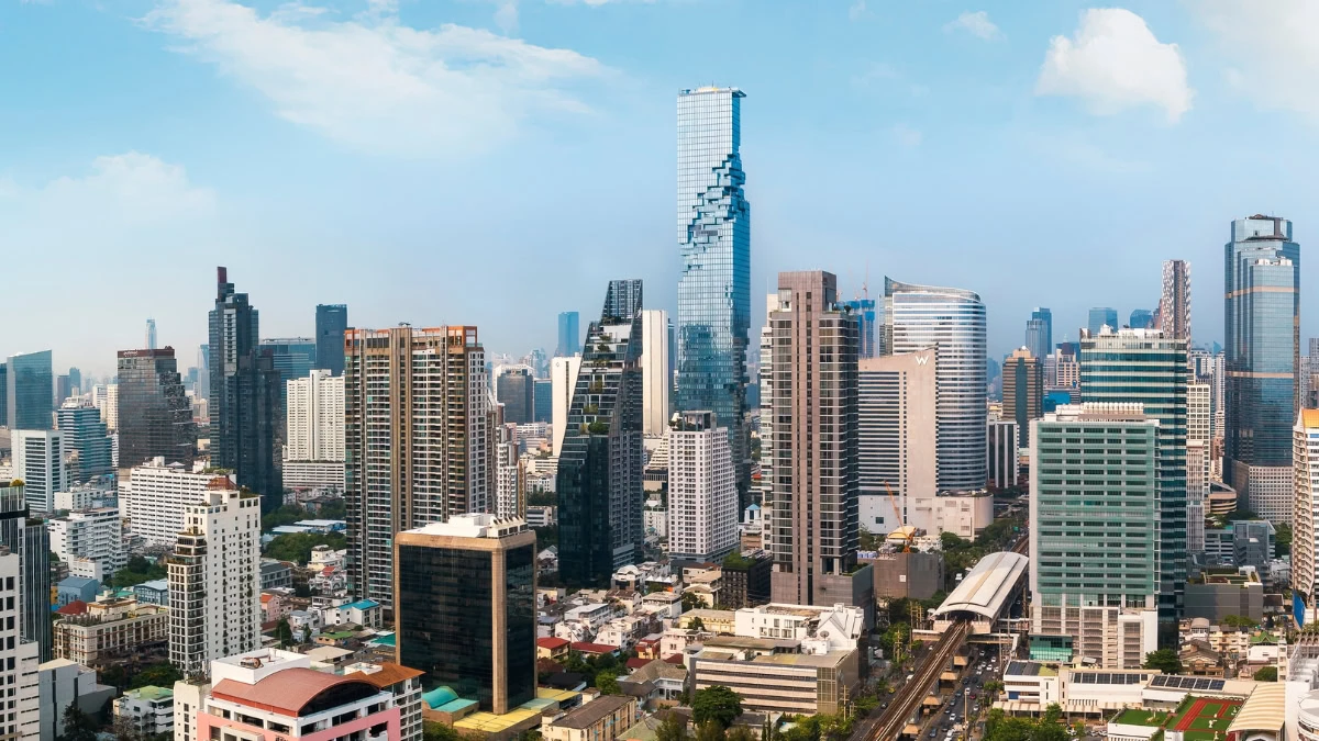 Skyline of a modern city with numerous high-rise buildings under a blue sky, urban density visible throughout the scene.