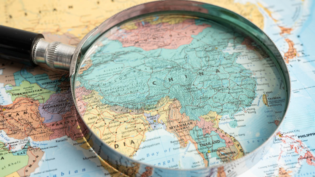 Magnifying glass over a map highlighting China and surrounding regions in Asia.