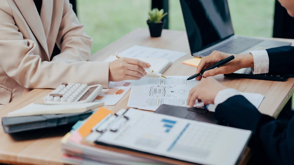 Business meeting with documents and laptop on desk.