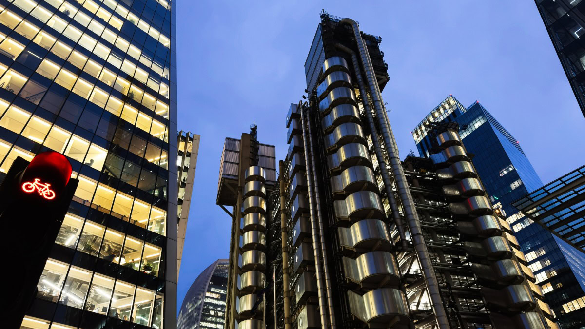 Modern skyscrapers in a city skyline with illuminated windows at dusk.